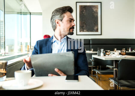 Businessman using digital tablet par restaurant fenêtre, Londres, Royaume-Uni Banque D'Images