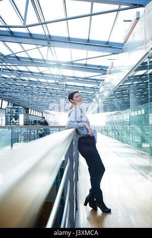 Happy businesswoman leaning against balcon bureau Banque D'Images