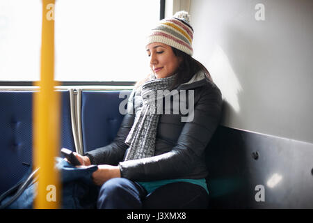 Femme voyageant sur le bus looking at smartphone Banque D'Images