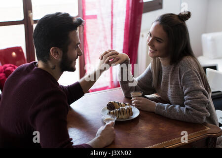 Couple sitting at table tenant les mains, boire du café Banque D'Images