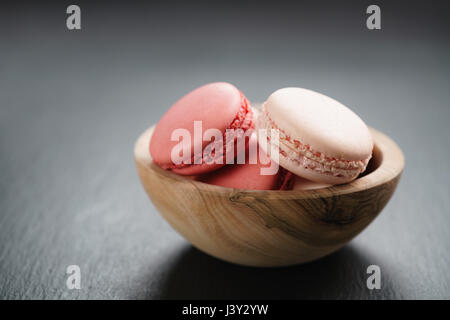 Macarons roses dans un bol sur fond ardoise with copy space Banque D'Images