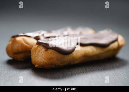 Deux éclairs au chocolat noir sur le dessus sur fond d'ardoise Banque D'Images