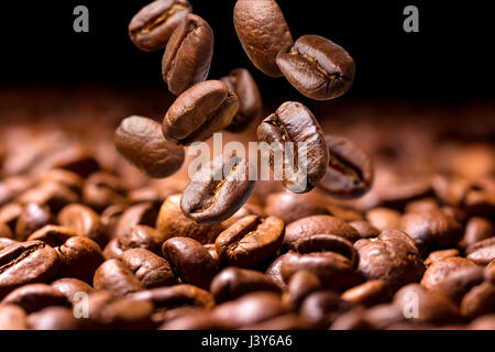 Les grains de café tomber close-up, battant les grains de café sur fond sombre Banque D'Images
