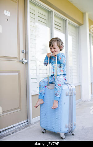 En pyjama garçon assis sur roues valise à l'extérieur chalet Banque D'Images