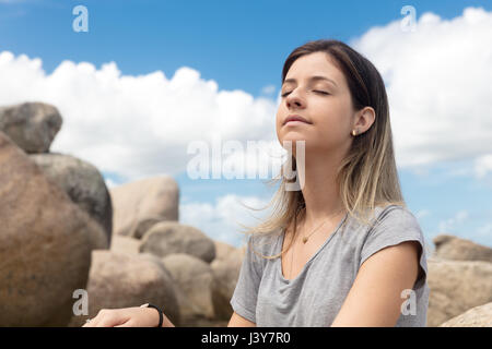 Teenage girl sitting on rocks, les yeux clos, de détente Banque D'Images