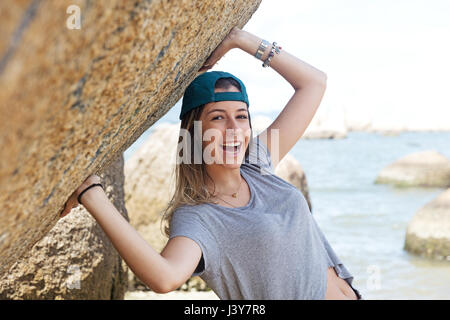 Portrait of teenage girl on rocks par mer à la caméra en souriant Banque D'Images