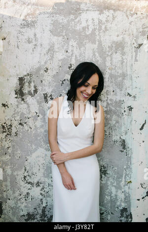 Mariée leaning against wall, smiling Banque D'Images