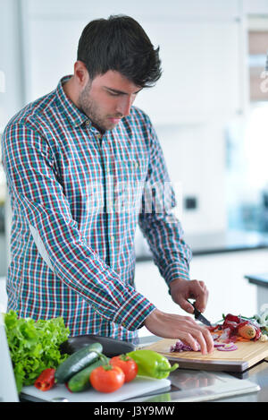 Bel homme cuisiner à la maison la préparation de salade en cuisine. Banque D'Images