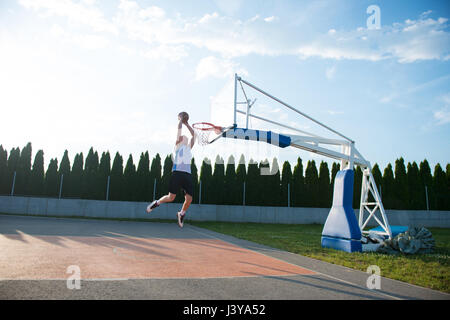 Jeune homme de saut et de faire un fantastique jeu slam dunk stree Banque D'Images