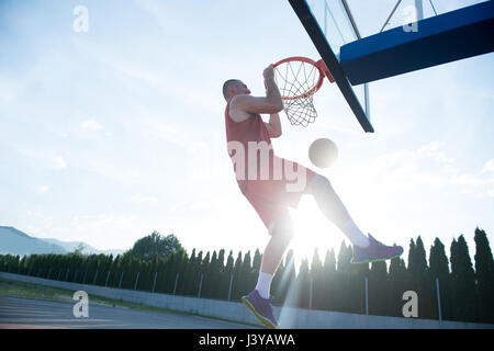 Jeune homme de saut et de faire un fantastique jeu slam dunk stree Banque D'Images