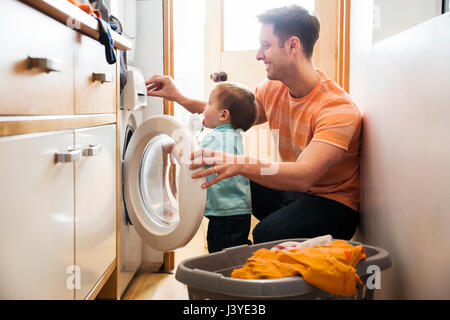 Le père et le petit garçon faire la lessive à la maison Banque D'Images