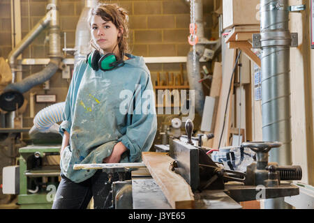 Portrait de jeune femme à côté de machines dans l'atelier du bois Banque D'Images