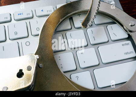 Concept de la criminalité en ligne. Les menottes sur le clavier. Banque D'Images