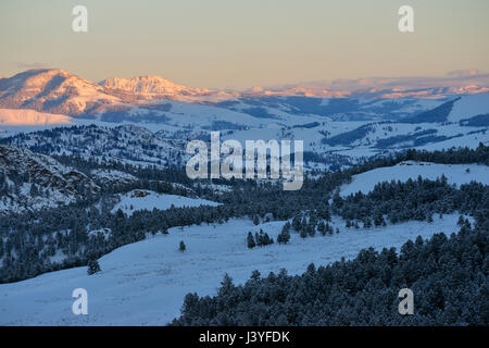 Scenic aperçu au cours de la large vallées ouvertes du Parc National de Yellowstone en hiver, les collines et montagnes couvertes de neige dans la dernière lumière du soir. Banque D'Images