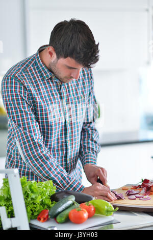 Bel homme cuisiner à la maison la préparation de salade en cuisine. Banque D'Images