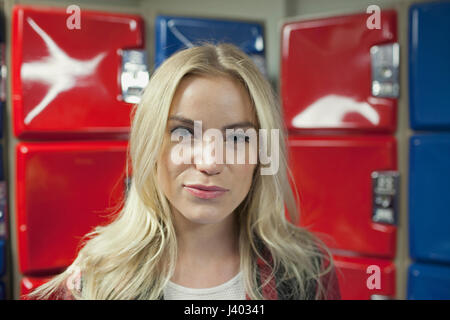 Une jeune femme en face de certains casiers rouge et bleu. Banque D'Images