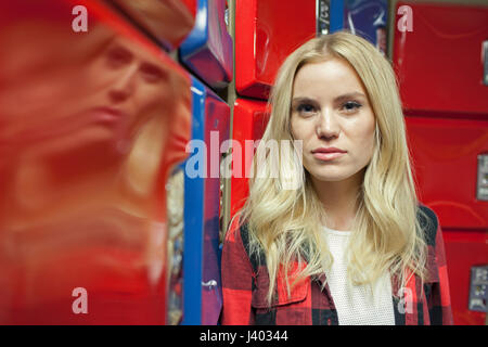 Une jeune femme en face de certains casiers rouge et bleu. Banque D'Images