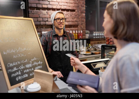 Barman et femme de payer par carte de crédit au café Banque D'Images