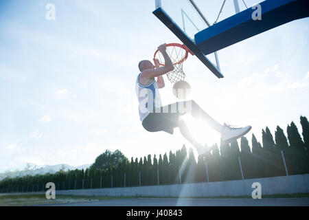 Jeune homme de saut et de faire un fantastique jeu slam dunk stree Banque D'Images