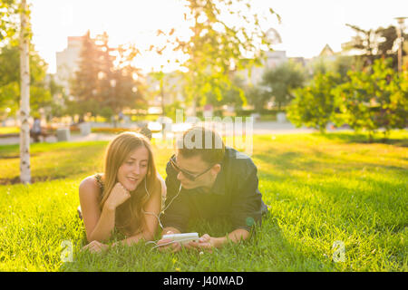 L'été, l'amour et personnes concept - close up of teenage couple lying on grass avec écouteurs et écouter de la musique. Banque D'Images