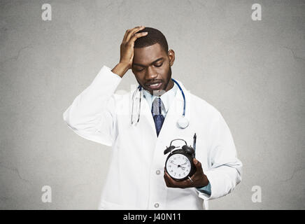 Closeup portrait accablé avec programme occupé professionnel de la santé médecin, infirmière, dentiste avec stéthoscope holding réveil court de ti Banque D'Images