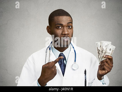 Closeup portrait avide avare grincheux professionnel de la santé, male doctor holding, pointant son argent dollars dans la main fond noir isolé. Banque D'Images