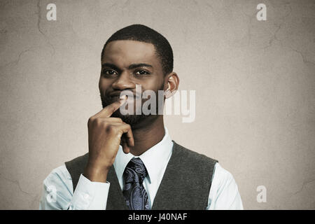 Closeup portrait jeune homme d'affaires perplexes penser profondément à décider quelque chose de doigt sur les lèvres à fond noir isolé confus. Emotio Banque D'Images