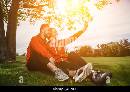 Sport homme et femme faisant autoportraits in park Banque D'Images