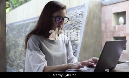 Femme dans les verres utiliser ordinateur portable. Businesswoman working on computer durant les vacances. 4K Banque D'Images