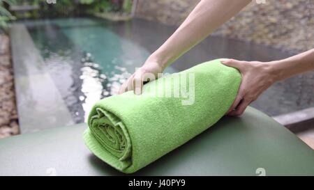 Close-up shot of woman putting fresh serviette sur une chaise longue près de la piscine dans l'hôtel en pays tropical. Banque D'Images