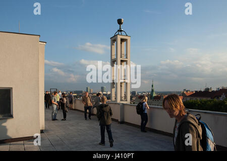 Personnes visitent la terrasse de toit de la Maison de la congrégation de l'Église hussite tchécoslovaque (Husův sbor) dans le quartier de Vinohrady à Prague, en République tchèque, le 10 juin 2016, l'occasion de visiter généralement fermées certaines parties de l'architecture religieuse durant le festival annuel monuments Nuit des Eglises (AC) kostelů. Le clocher fonctionnaliste de la congrégation conçu par l'architecte moderniste Tchèque Pavel Janák et construit en 1930-1935 vu dans l'arrière-plan. Banque D'Images