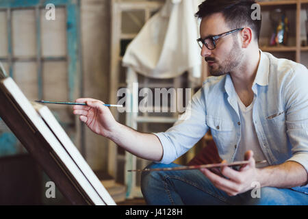 L'école d'art peinture artiste masculin avec de l'huile sur toile en studio Banque D'Images