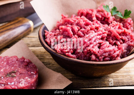 La viande de boeuf haché cru organique et burger steak escalopes prête à préparer sur la table rustique Banque D'Images
