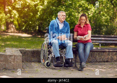 Homme handicapé en parc de passer du temps ensemble avec sa fille livre lecture outdoor Banque D'Images