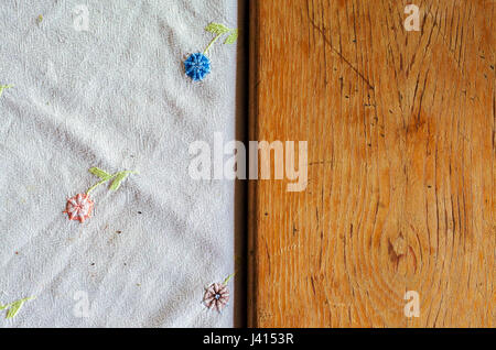 Broderie décorative en forme de fleurs sur fond blanc feuille d'un côté et la texture en bois d'une table de l'autre côté. Banque D'Images