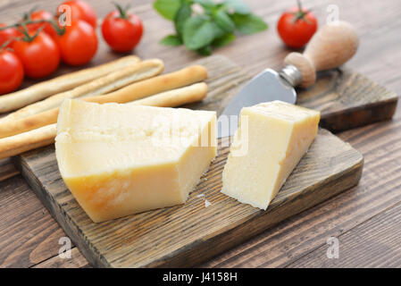 Le Parmesan sur une planche à découper avec le basilic et le couteau sur fond de bois Banque D'Images