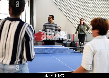 Les gens d'affaires de démarrage à jouer au tennis de table ensemble pendant la pause Banque D'Images