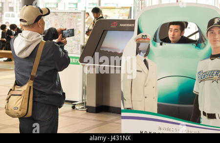 Hakodate, Japon - 3 avril 2017 : un japonais prenant une photo d'un ami avec son mobile dans une publicité de train JR Hokkaido shinkansen à la JR Banque D'Images