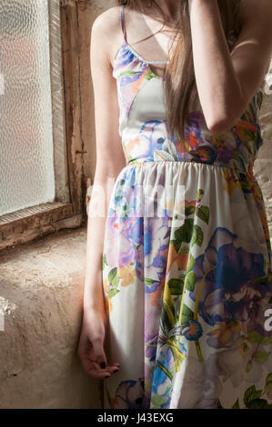 Gros plan d'une jeune femme portant une robe d'été debout près de la fenêtre Banque D'Images