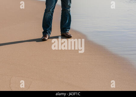 Homme portant chaussures brunes debout sur la plage Banque D'Images