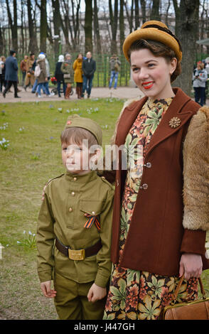 Saint-pétersbourg, Russie - Mai 9, 2017.Modèles - une fille habillée d'une tenue au printemps de 1940 et un garçon en uniforme à un spectacle rétro dans le jardin d'été à Saint-Pétersbourg à l'occasion de la célébration du Jour de la victoire.. Banque D'Images