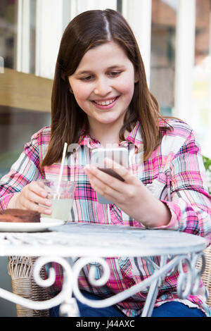 Jeune fille au Café Lecture Text Message On Mobile Phone Banque D'Images