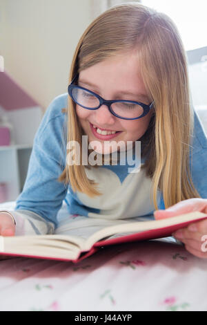 Young Girl Lying On Bed Reading Book Banque D'Images