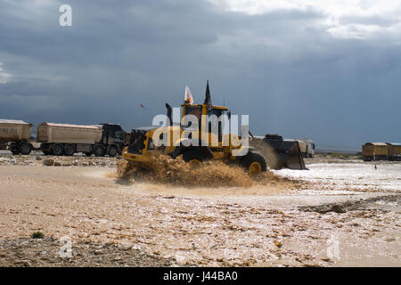 Les travaux routiers, les conditions de travail sur la route, les voitures d'essayer de passer à travers l'inondation et de la machinerie lourde est le nettoyage de la route Banque D'Images