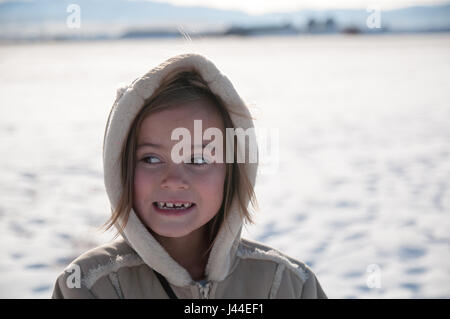 Scène d'hiver avec une jeune fille portant un manteau à capuchon et à la recherche sur le côté tout en souriant. Banque D'Images