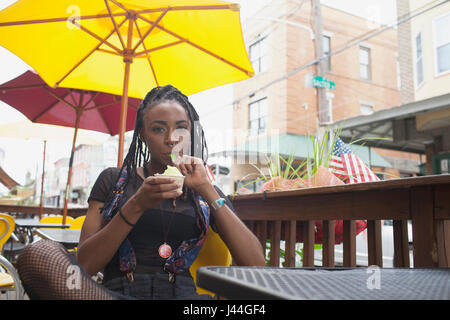 Une jeune femme de manger du yogourt glacé. Banque D'Images