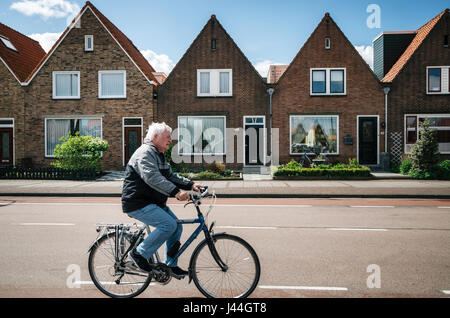 Volendam , Pays-Bas - 26 avril, 2017 : habitant du village de Volendam en vélo en face de la typique des maisons traditionnelles de la pêche néerlandais un vil Banque D'Images