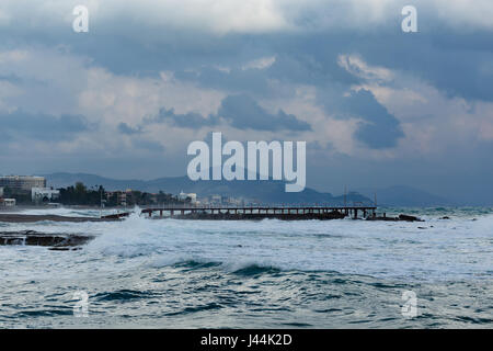 Seascape avec de puissantes vagues qui côte de ville méditerranéenne pendant une tempête et les montagnes en arrière-plan flou et ciel avec nuages gris Banque D'Images