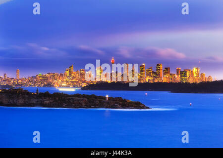 Panorama de la ville de Sydney CBD dans une distance le long de la baie de Sydney derrière la tête du Sud avec Hornby phare au coucher du soleil. Banque D'Images