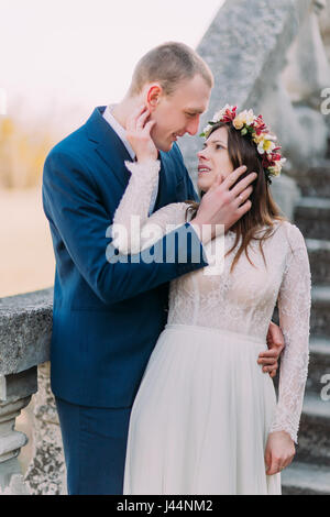 Heureux de Faire place au marié avec sa jolie mariée tandis que les deux debout sur un escalier en pierre. Portrait demi-longueur Banque D'Images